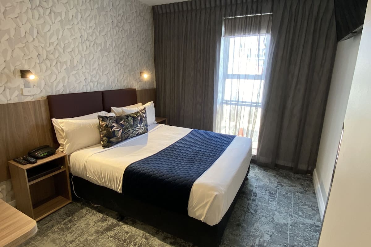 Ein modernes Hotelzimmer mit einem großen Bett, einem Deckenventilator, einem Flachbildfernseher und einer Wand mit Steinoptik.