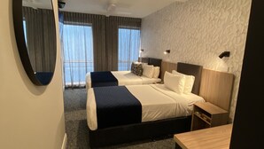Habitación de hotel con dos camas, un espejo grande, un ventilador de techo y una pared con textura.