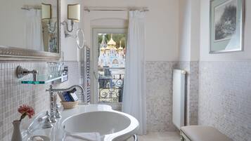 A bathroom with a white sink, mirror, and a view of a colorful building through a window.