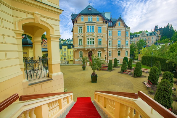A grand building with a red carpeted staircase leading to an ornate balcony.