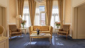 A spacious room with a large sofa, two armchairs, a coffee table, and a chandelier.