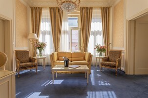 A spacious room with a large sofa, two armchairs, a coffee table, and a chandelier.