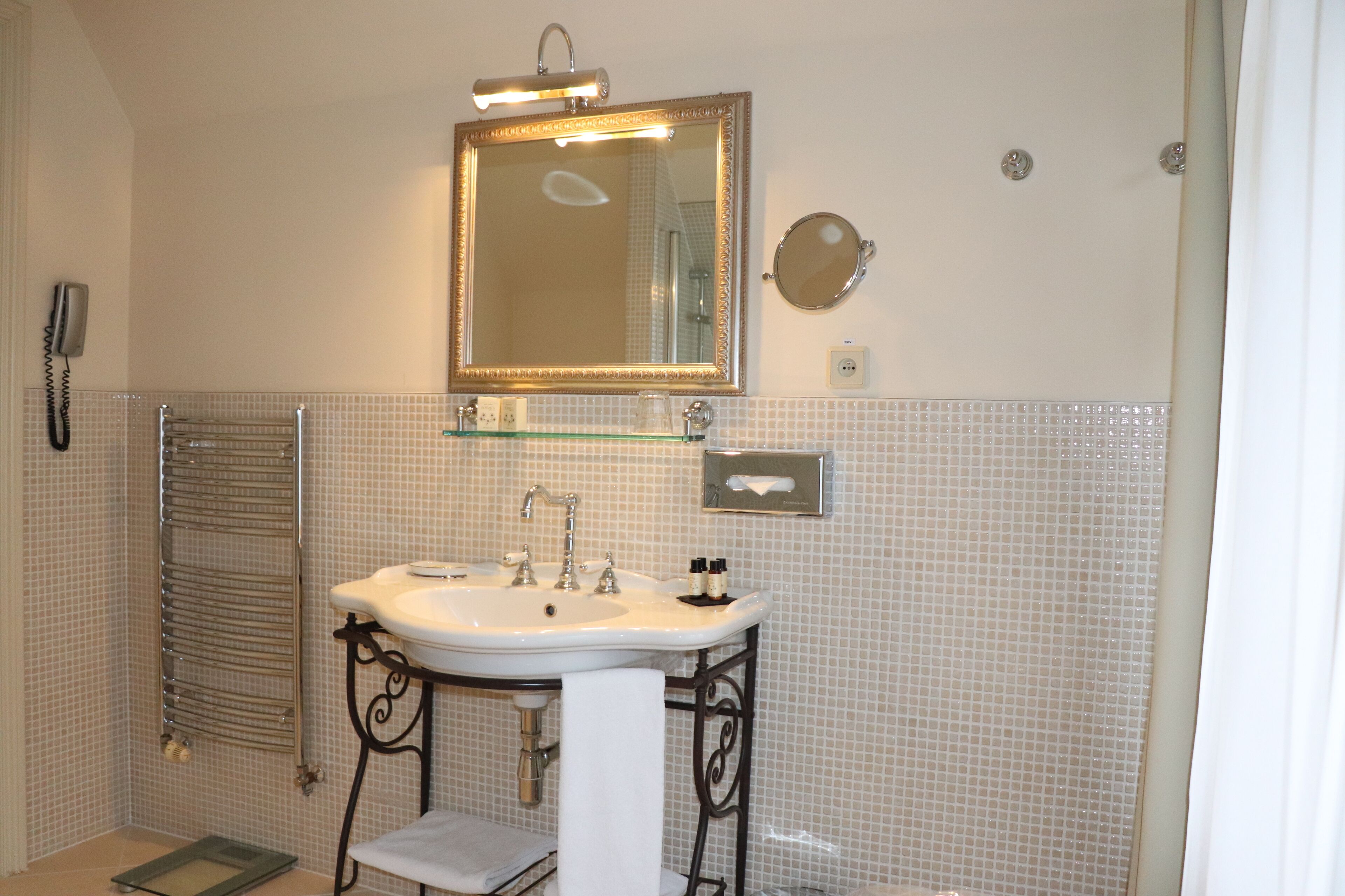 A bathroom with a white sink, a mirror, a towel rack, and a glass shelf.
