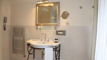 A bathroom with a white sink, a mirror, a towel rack, and a glass shelf.