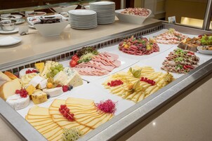 A buffet with various cheeses, meats, and fruits.