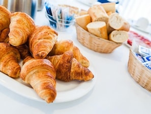 A plate of croissants and a basket of baguettes on a table. - Viadero (Noja)