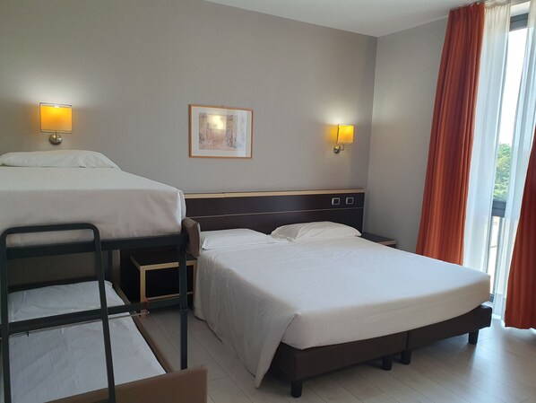 Habitación de hotel con dos camas, una mesita pequeña y una silla. Hay dos lámparas de pared y un cuadro en la pared.