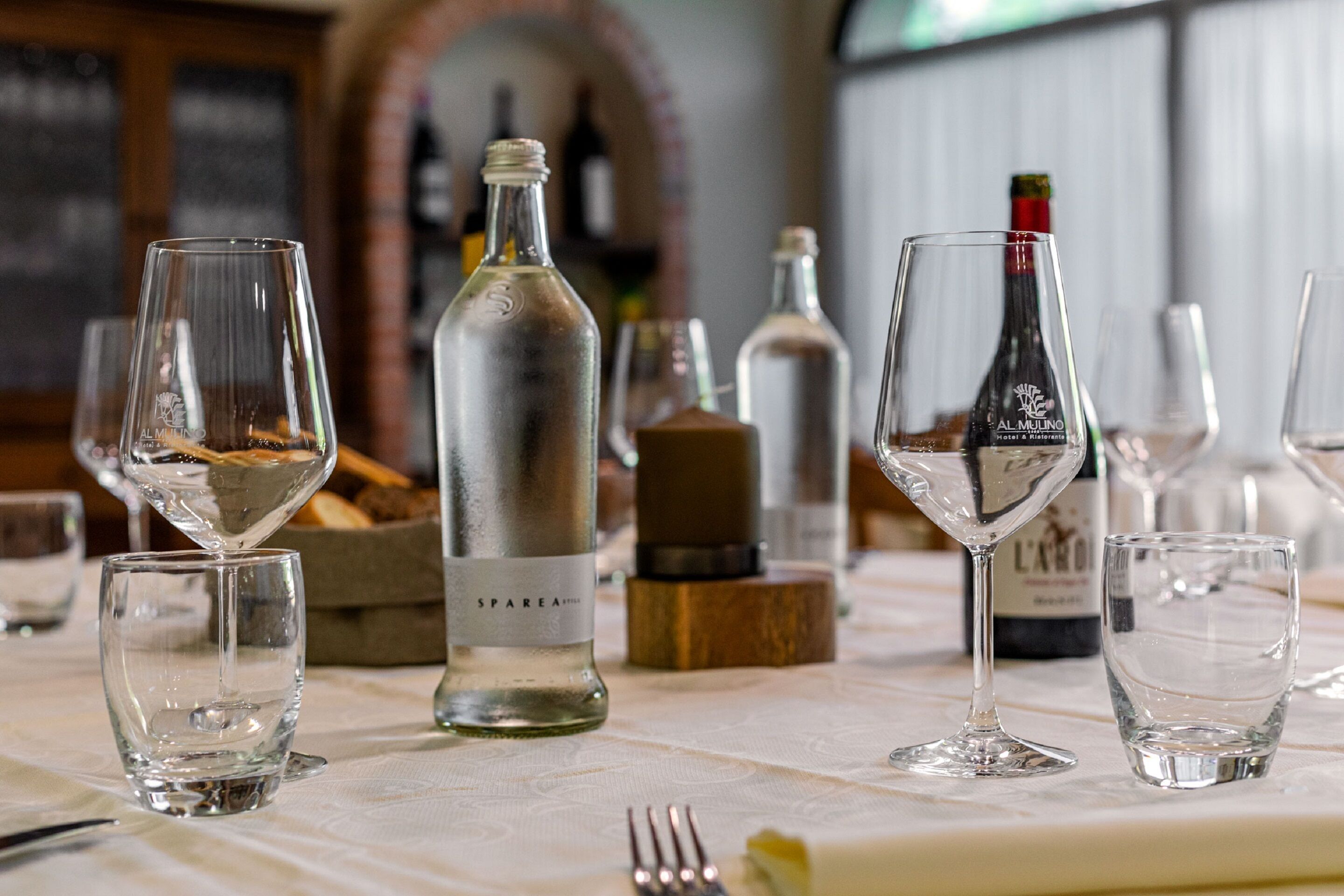 Une table dressée avec des verres à vin, des bouteilles et une fourchette, ce qui indique qu’un repas ou une dégustation va avoir lieu.