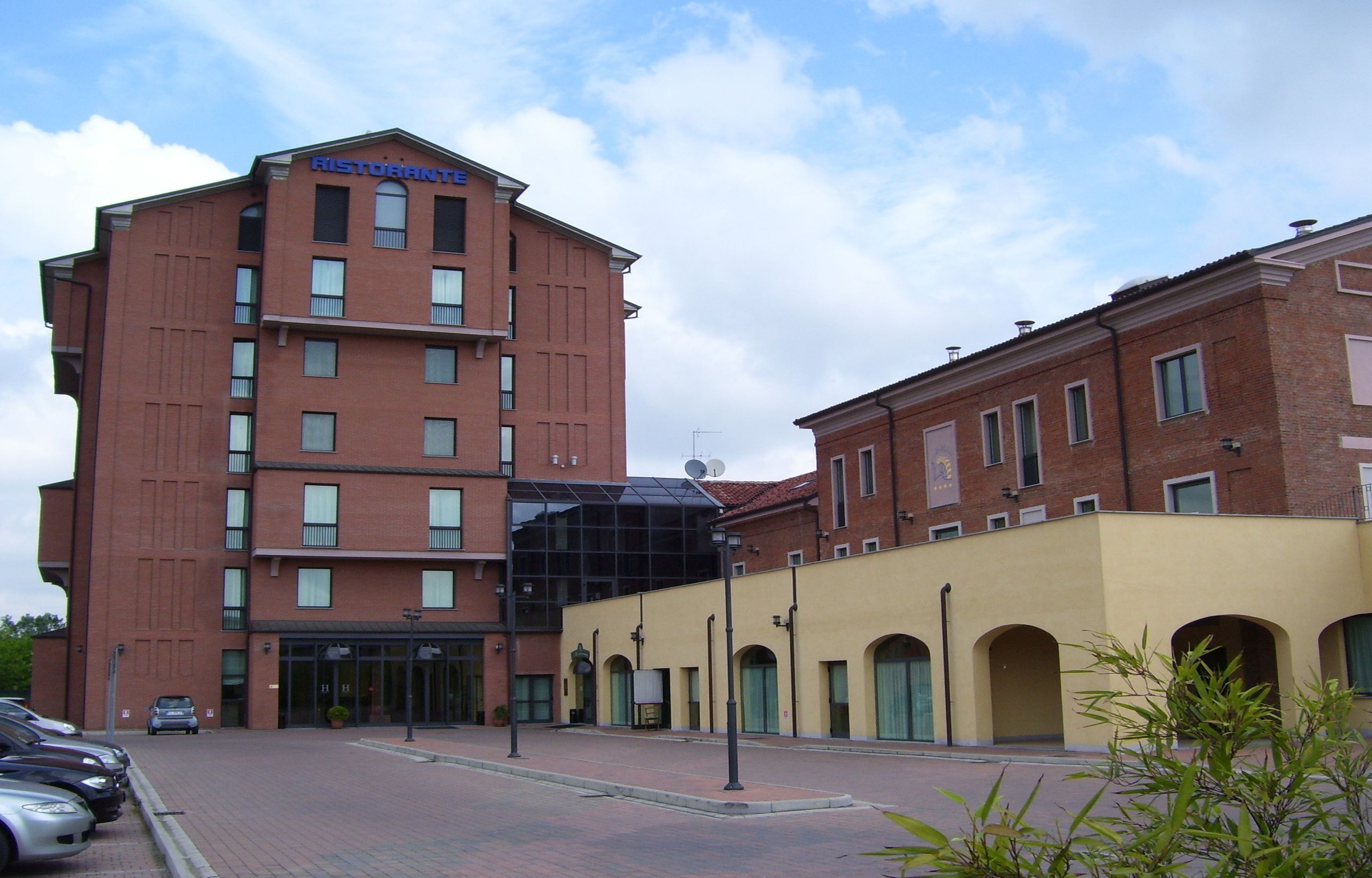 A multi-story hotel with a modern design, featuring a prominent glass entrance and a brick facade.