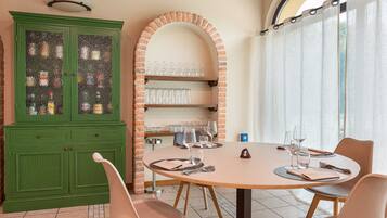 Un comedor con una mesa redonda, sillas, un armario verde con puertas de cristal y un arco de ladrillo.