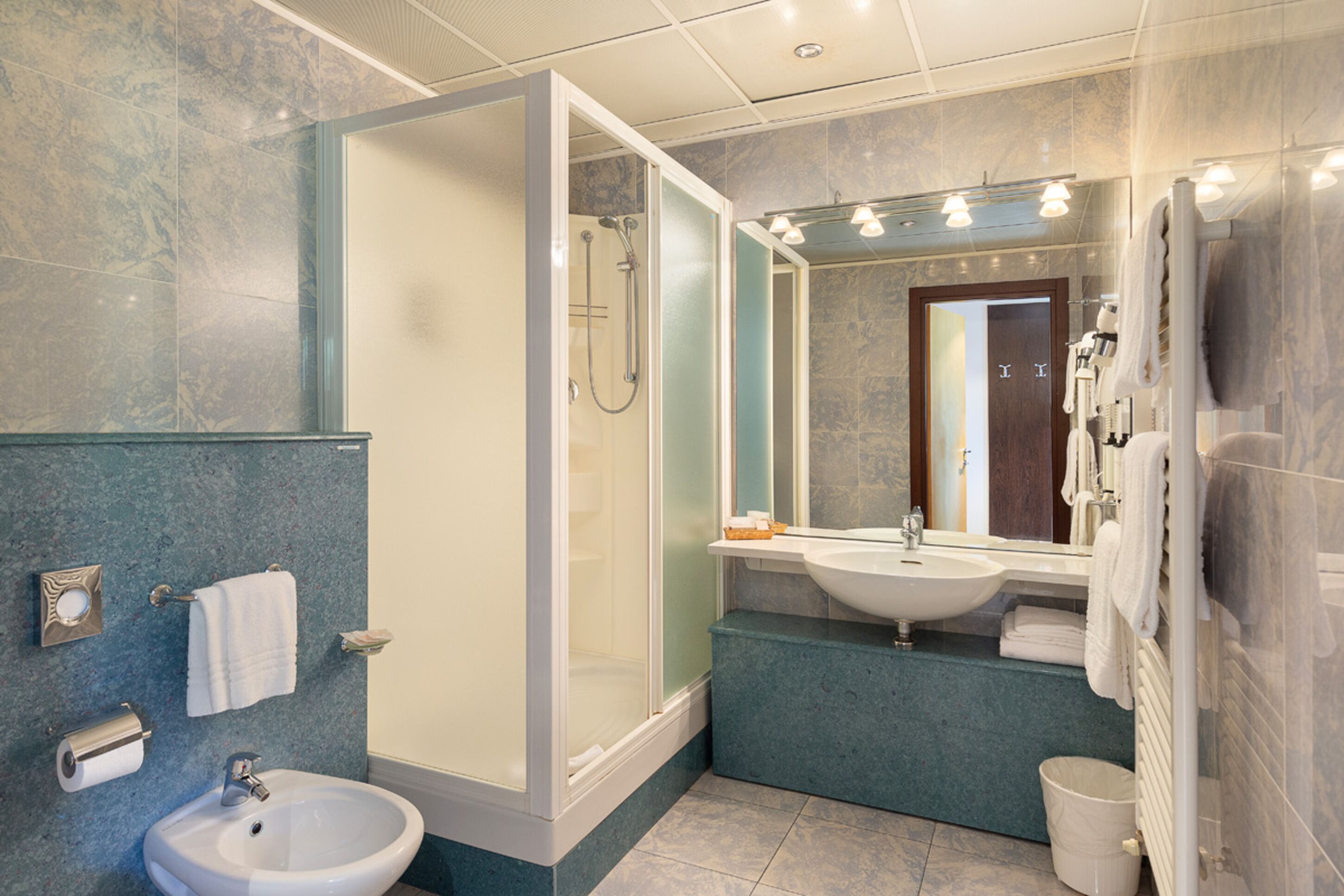 A modern bathroom with a glass-enclosed shower, a sink, and a mirror.