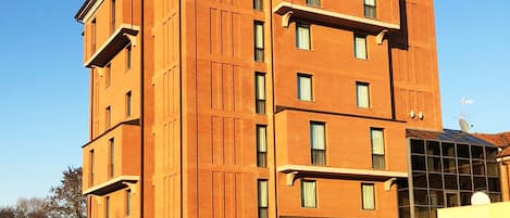 A multi-story hotel with a prominent entrance and a parking area in front.