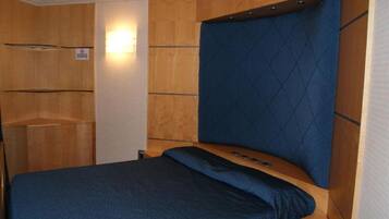 Un dormitorio con cama, cabecera de madera y una pequeña repisa.
