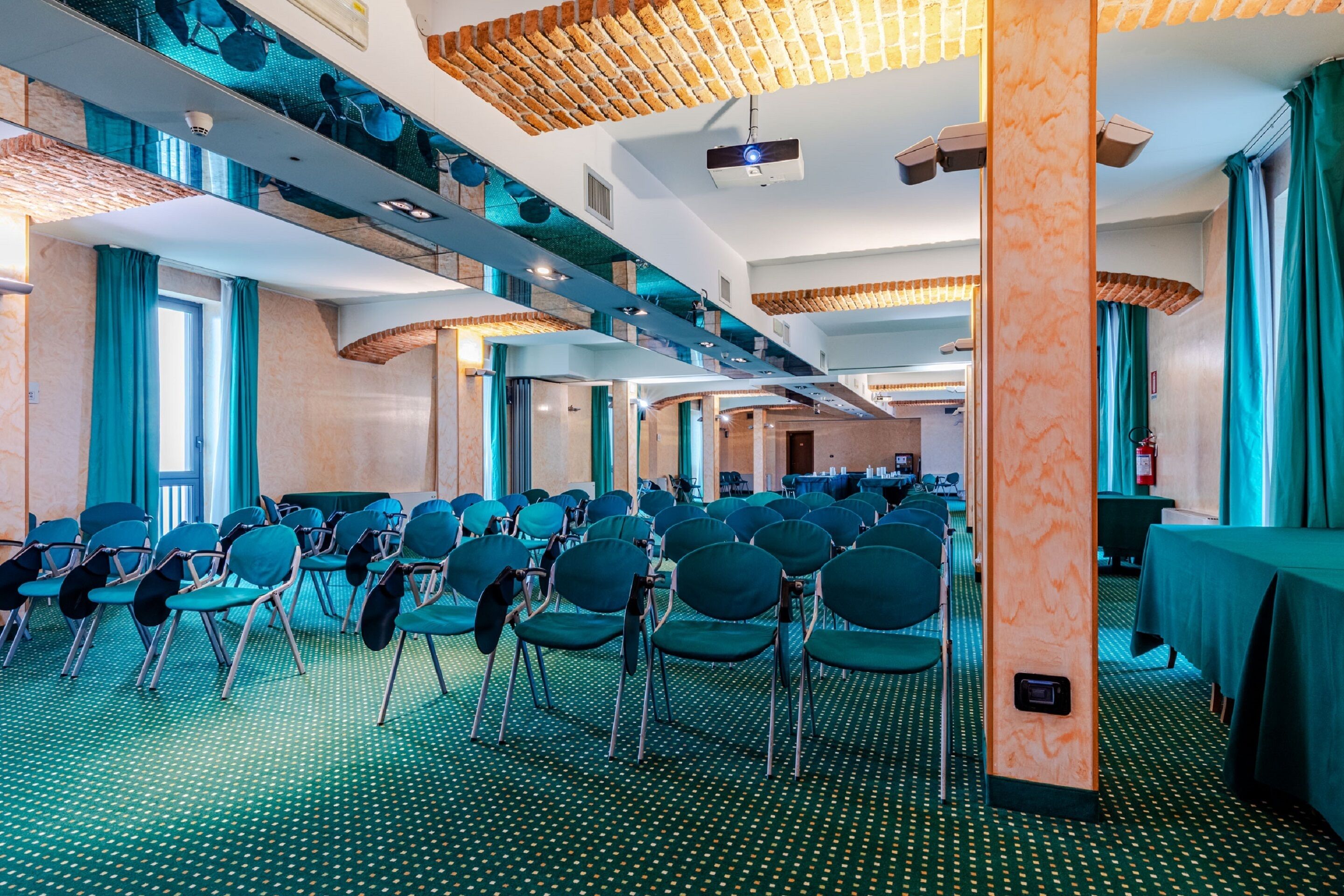 A conference room with rows of chairs, a projector, and a large screen.