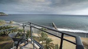 Ein Balkon mit Blick auf den Ozean, eine Holzpier und ein Strand mit Palmen.