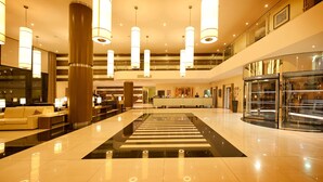 Eine großzügige Lobby mit einem schwarz-weißen Streifenboden, mehreren Sitzbereichen und einem Glasturm.