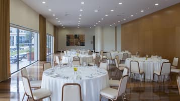 A conference room with multiple round tables set for dining, equipped with chairs and table settings.