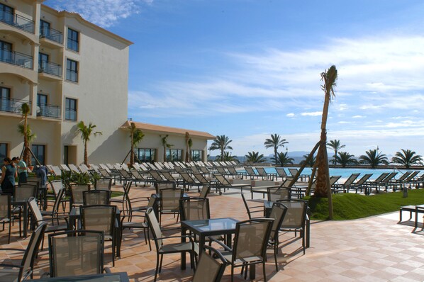A resort pool area with sun loungers and tables, a building with balconies, and palm trees. - Vila Gale Santa Cruz Resort Hotel (Santa Cruz)