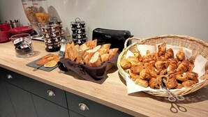 A kitchen counter with bread, pastries, and condiments.