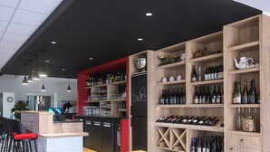 A bar area with wooden shelves stocked with bottles, glasses, and a refrigerator.