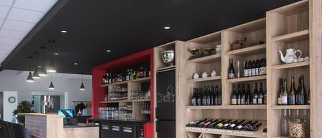 A bar area with wooden shelves stocked with bottles, glasses, and a refrigerator.