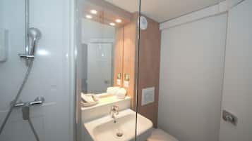 Een moderne badkamer met een douchecabine van glas, een wastafel en een toilet.