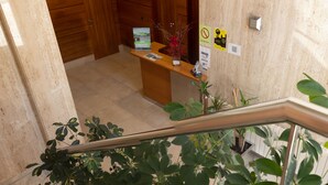 A reception desk with a wooden counter, a plant, and a sign with a QR code. - Hotel Ciudad De Lugo (Lugo)