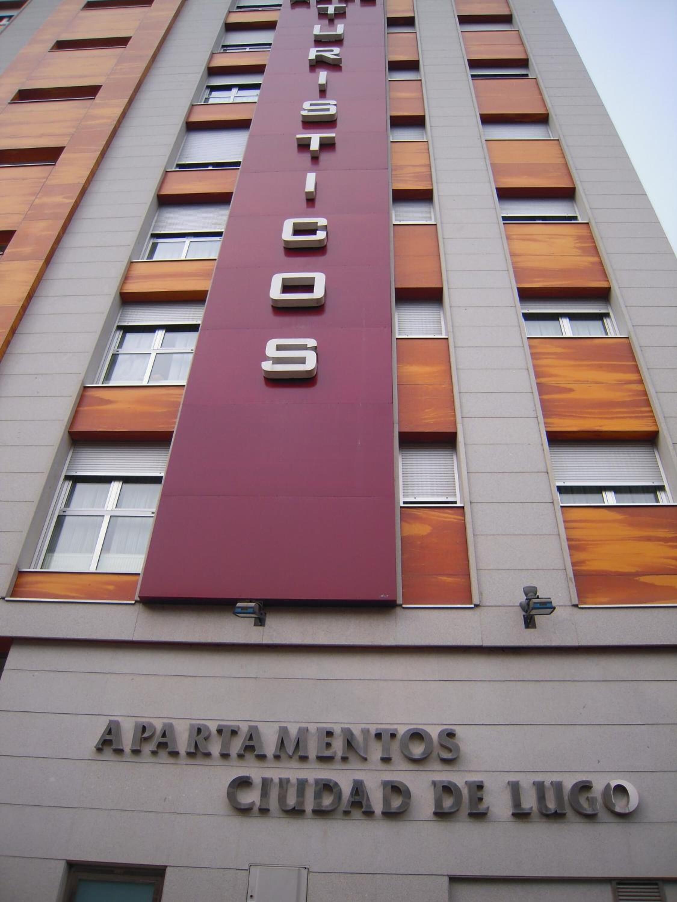 Un edificio con un letrero vertical color borgoña que dice 