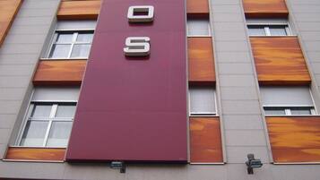 Un edificio con un letrero vertical color borgoña que dice
