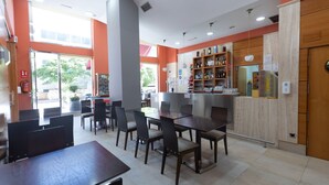 A restaurant with a bar area, multiple tables and chairs, and a display of bottles and glasses. - Hotel Ciudad De Lugo (Lugo)