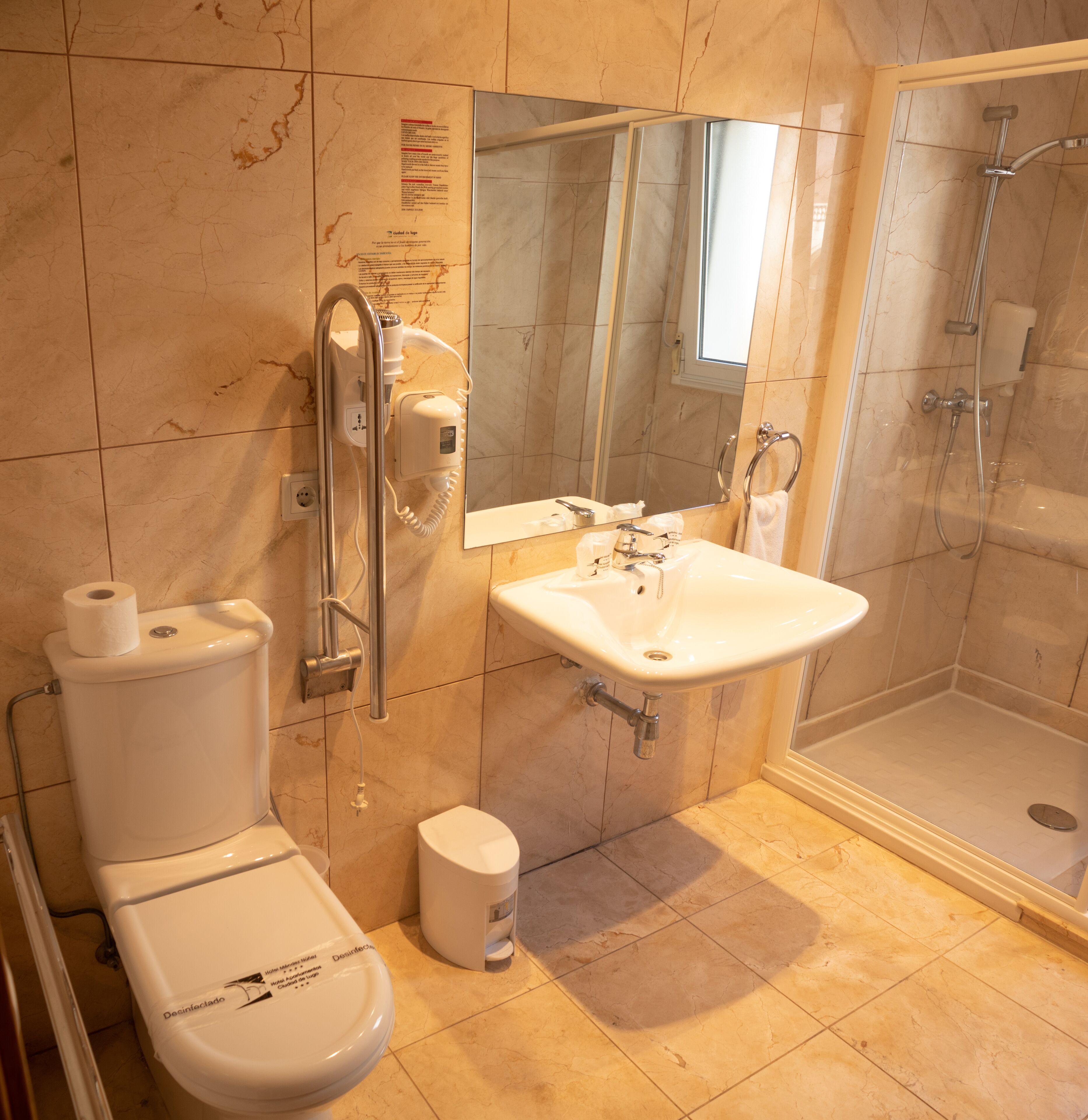 A bathroom with a toilet, sink, mirror, and shower.