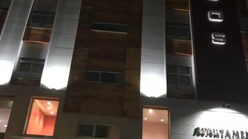 Un edificio de varios pisos con ventanas iluminadas y un letrero que dice "APARTMENT CLUB".