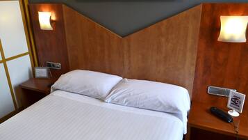 Habitación de hotel con cama, mesita de noche con teléfono y cartel que indica Wi-Fi gratuito.