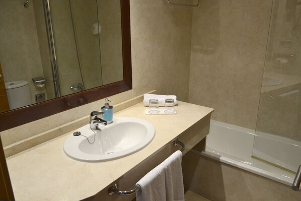 A bathroom with a sink, mirror, and bathtub.