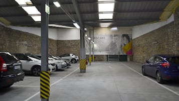 Un garaje de estacionamiento con varios coches aparcados, pisos de concreto y un mural en la pared trasera.