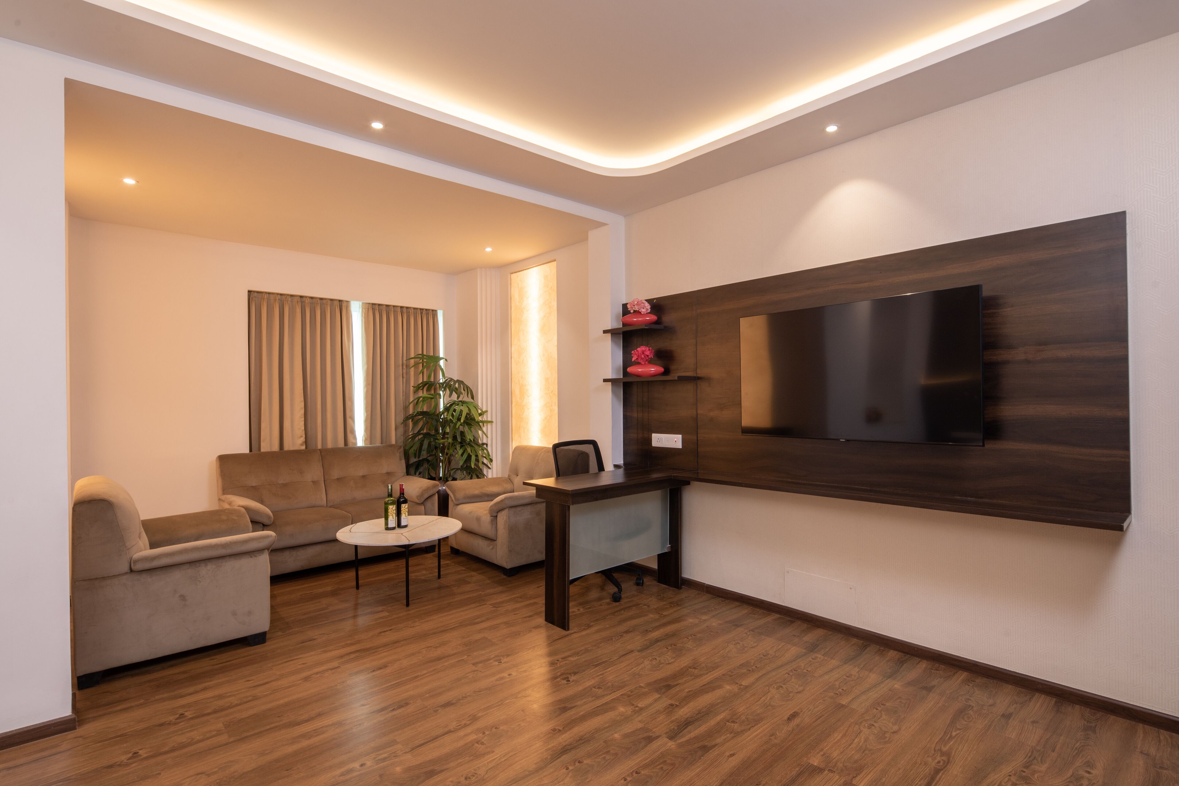 A modern living room with a flat-screen TV, a sofa, a coffee table, and a desk.