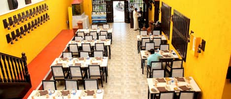 A restaurant with multiple tables and chairs, a staircase, and a yellow wall.