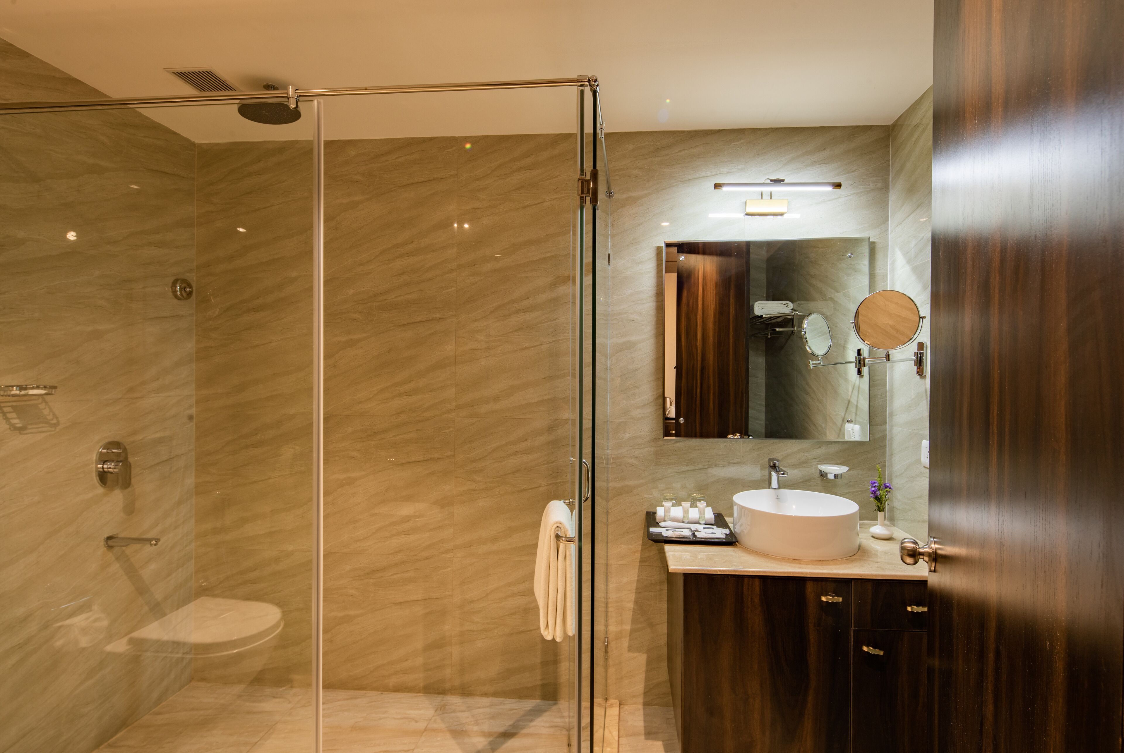 Un baño moderno con ducha de vidrio, tocador con lavabo y espejo.