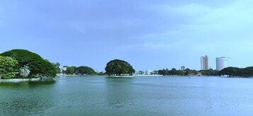 A calm lake with trees and buildings in the background.