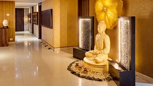 A hallway with a Buddha statue, a large yellow umbrella, and illuminated panels. - Goldfinch Hotel Bangalore (Bengaluru)