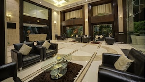 A spacious living area with leather sofas, a glass coffee table, and a large aquarium. - Goldfinch Hotel Bangalore (Bengaluru)