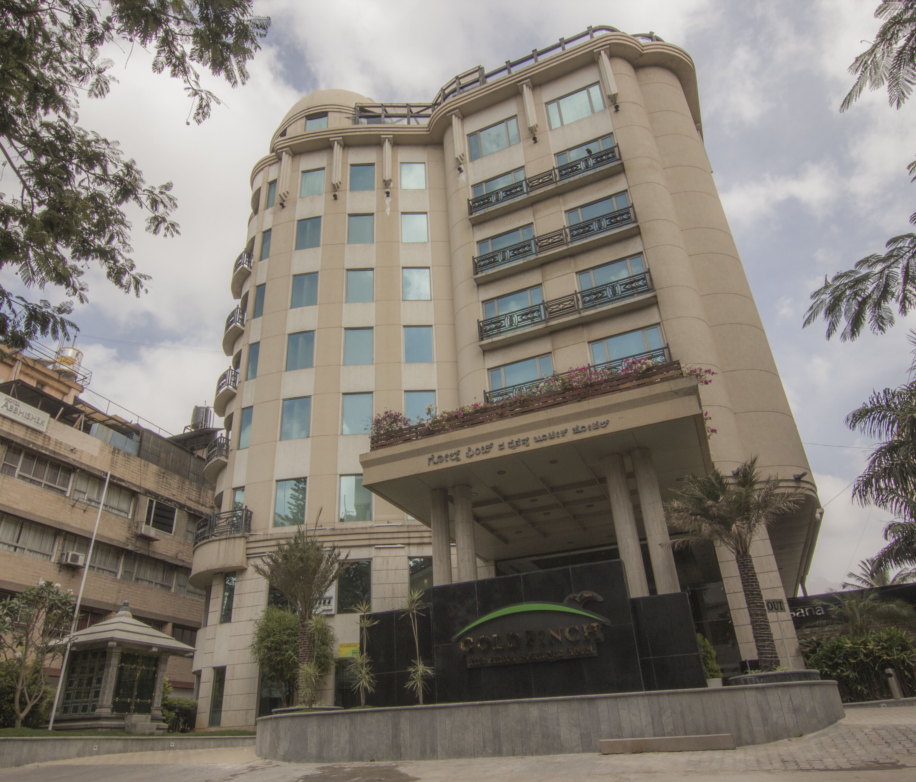 A multi-story hotel with a curved facade, balconies with railings, and a sign indicating it is a Goldinche hotel.