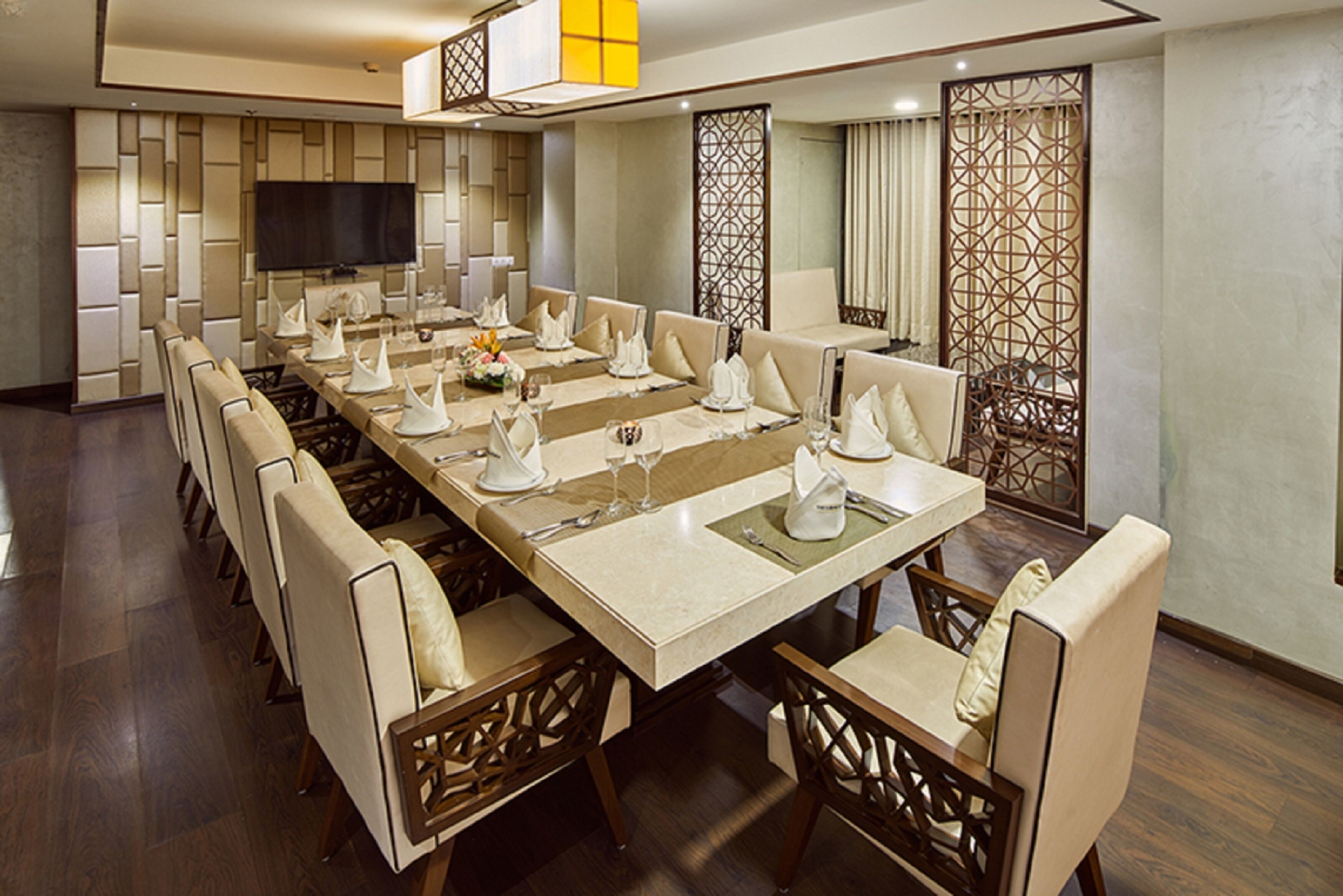 A conference room with a long table, chairs, and a television on the wall.