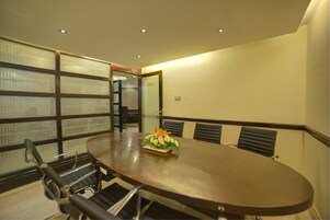 A conference room with a large oval table, black chairs, and a floral centerpiece.
