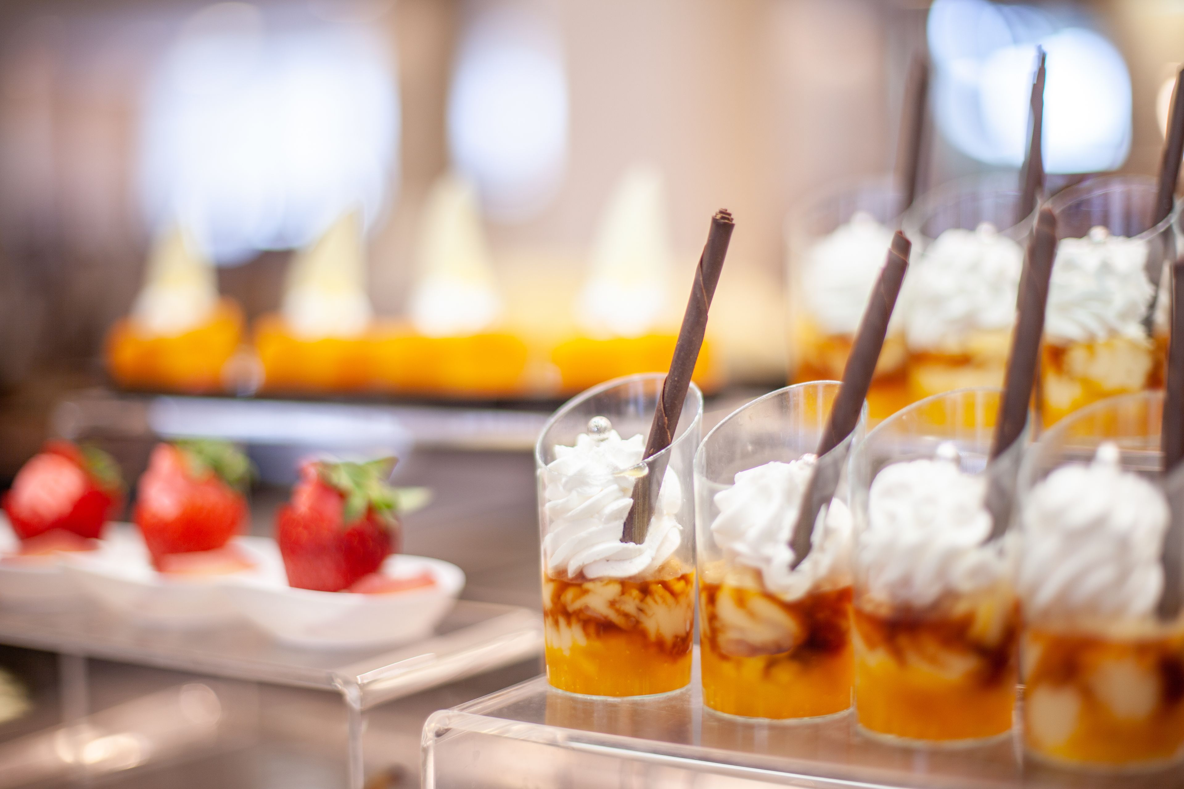 Copas de postre con crema batida y palitos de chocolate sobre una bandeja.