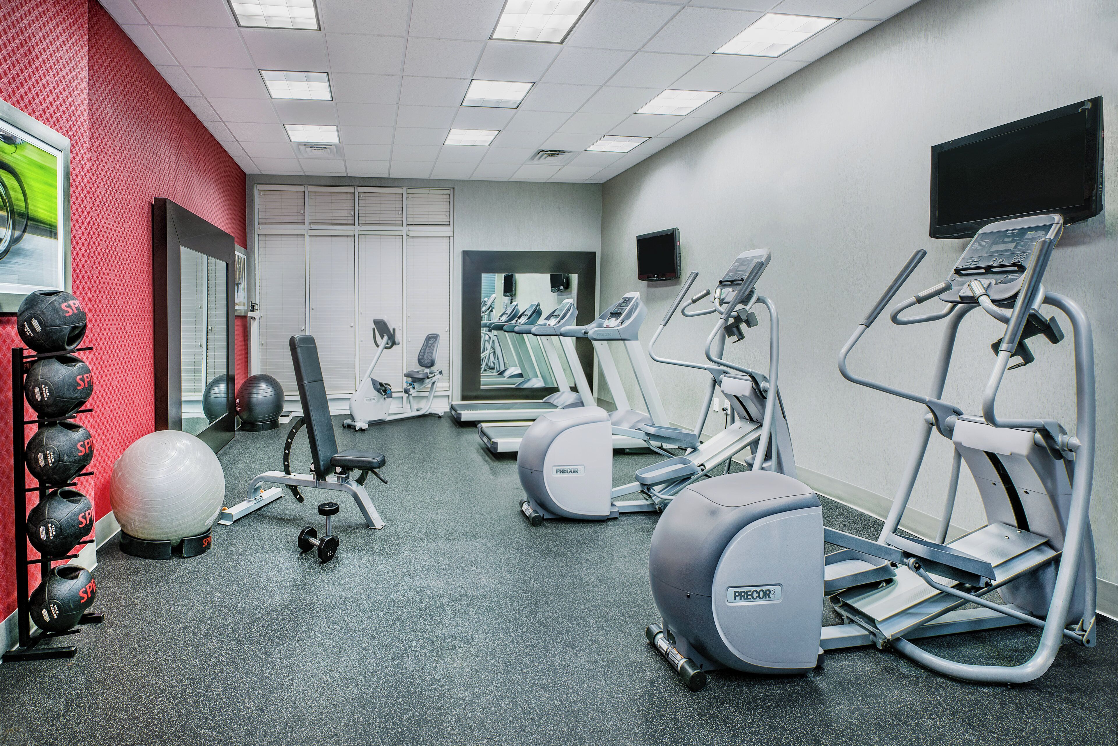 Una palestra con tapis roulant, ellittiche, una cyclette e pesi liberi.