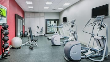A gym with treadmills, elliptical machines, a stationary bike, and free weights.