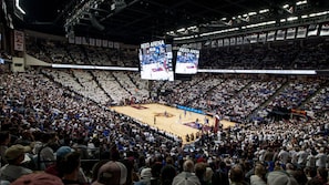 Une vaste salle intérieure dotée de gradins à plusieurs niveaux, d’écrans d’affichage numériques et d’un terrain de basket-ball.