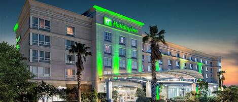 Un hotel Holiday Inn con entrada despejada, varios pisos y un jardín bien cuidado.