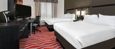 A hotel room with two beds, a desk with a flat-screen TV, a chair, and a red and gray striped carpet.